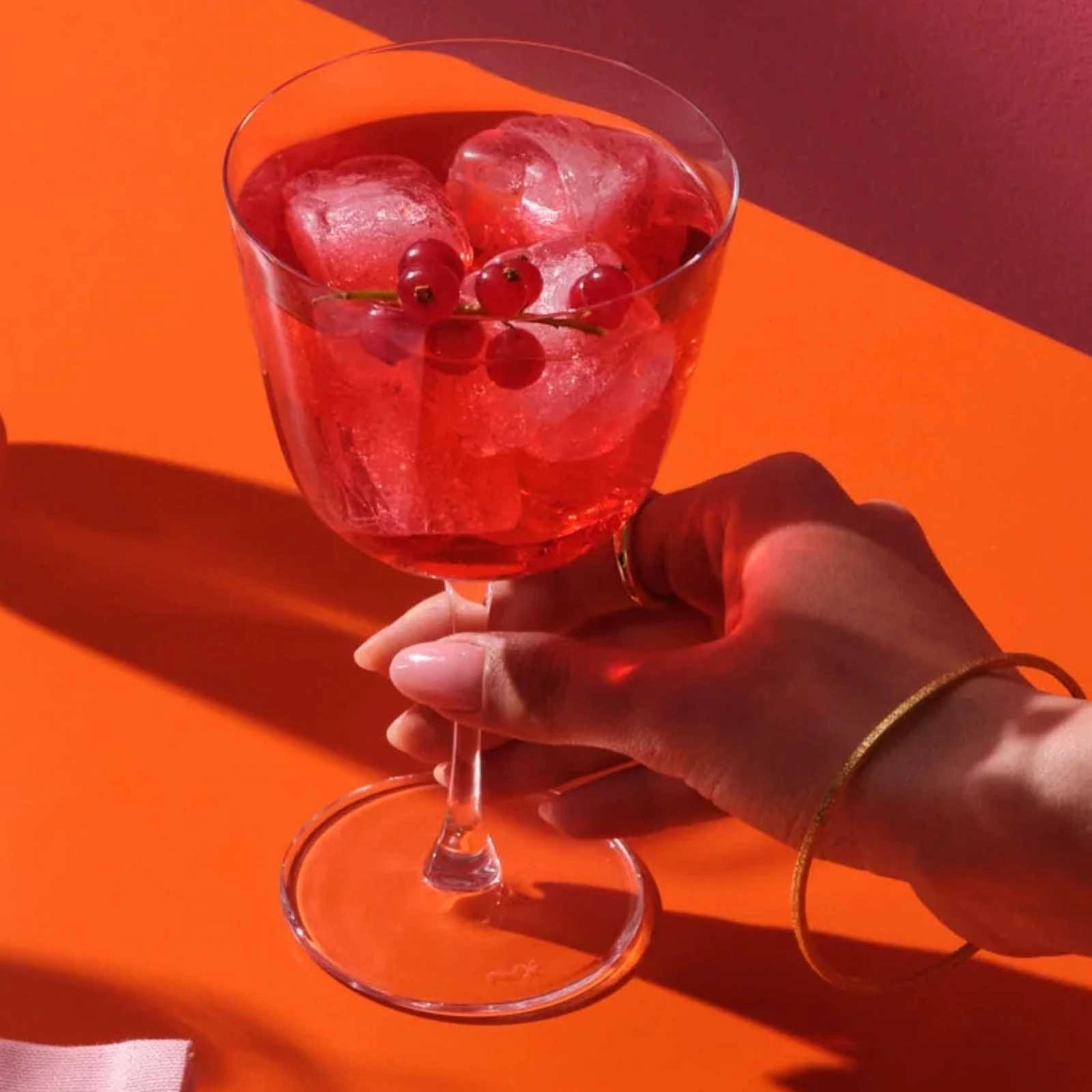 copa de spritz Bargiani de NUDE de 33 cl con un cóctel, sujeta por el tallo