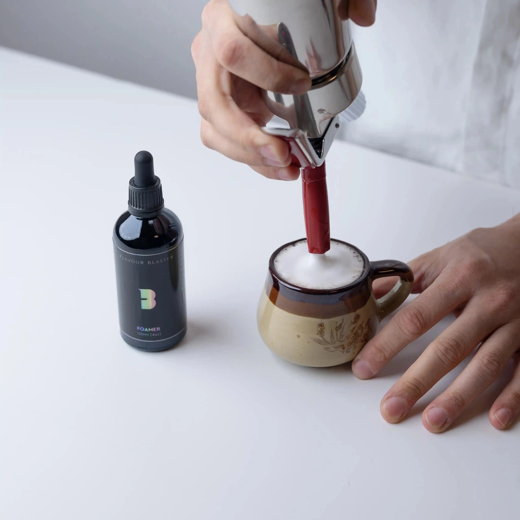 foamer cocktail Flavour Blaster: espuma hecha con sifón sobre una taza de cerámica, con la botella al lado